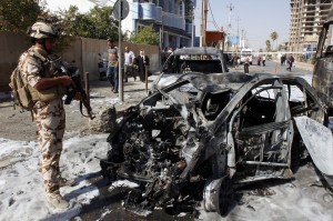 An Iraqi soldier stands next to a mangled car following a car bomb attack in Kirkuk [Xinhua]