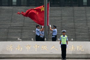 Chinese police officers raise the national flag outside the Jinan Intermediate People's Court in Jinan in eastern China's Shandong province [AP]