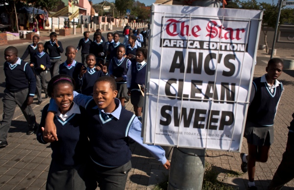 Schoolchildren walk past a newspaper placard reporting the election victory of Jacob Zuma's African National Congress (ANC) party, based on preliminary results, as the children leave after making a visit to the former house of the late South African President Nelson Mandela, in the Soweto township of Johannesburg, South Africa Friday, May 9, 2014 [AP]