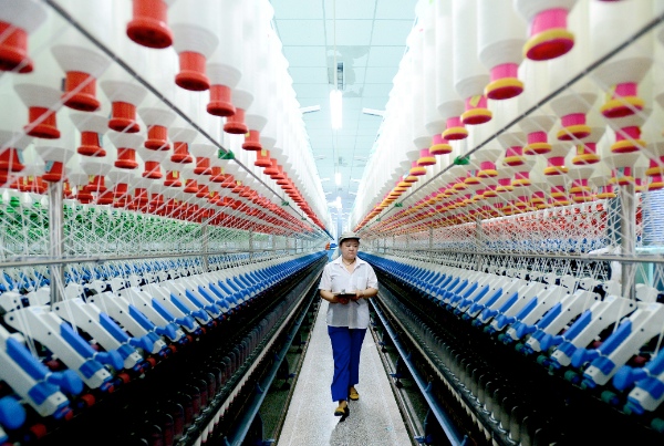  A labourer works at a spinning mill in Xiajin County, east China's Shandong Province, June 12, 2014 [Xinhua]