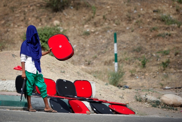  An Indian boy, with his face covered to protect himself from the sun, sells sunshades for car windows on a roadside in Jammu, India, Saturday, June 14, 2014 [AP]