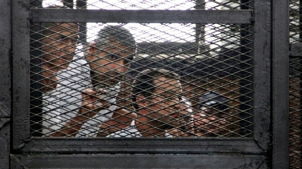 From left, Australian correspondent Peter Greste, Canadian-Egyptian acting bureau chief of Al-Jazeera Mohamed Fahmy, and Egyptian producer Baher Mohammed, appear in a defendant's cage in a courtroom in Cairo, Egypt, Monday, June 23, 2014 [AP]