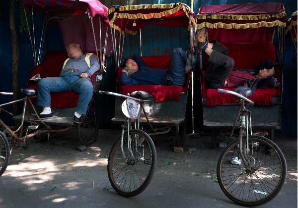 Chinese trishaw drivers take nap while waiting for customers at a hutong alley near the drum tower, a tourist spot in Beijing, China Wednesday, May 7, 2014 [AP]
