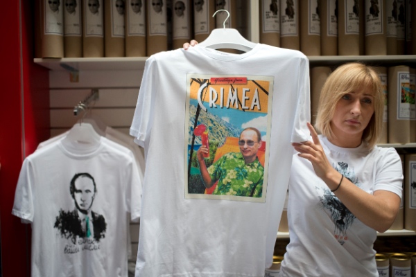 A shop assistant displays a T-shirt depicting Russian President Vladimir Putin and reading Greetings from Crimea at the biggest department store GUM on Moscow's Red Square, Wednesday, June 11, 2014 [AP]