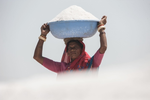 A laborer carries the raw salt at an ancient salt field in Devla-Nada area of Gujarat, India, May 1, 2014 [Xinhua]