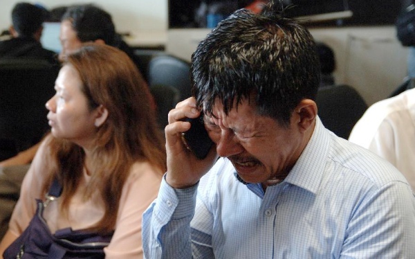 A relative of a passenger onboard missing Malaysian air carrier Air Asia flight QZ8501 breaks down while making a phone call at Juanda international airport in Surabaya in East Java of Indonesia on Dec. 28, 2014 [Xinhua]