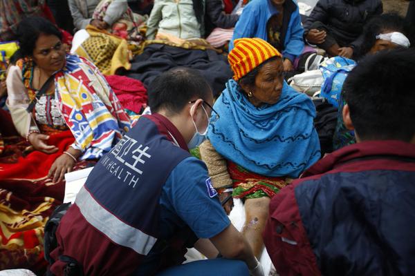 An injured Nepalese woman is ended to by a Chinese medical worker [Xinhua] 