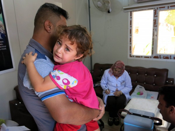 A man from a refugee camp waits to vaccinate his daughter in Baghdad, Iraq [Xinhua]